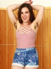 Joyful girl in shorts gladly demonstrates armpits and hairy peach