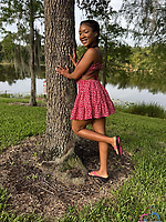 Bold babe in pink dress and white bikini poses solo by trees and lake