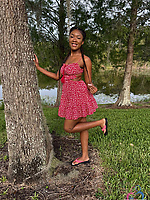 Bold babe in pink dress and white bikini poses solo by trees and lake